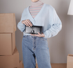 Young woman's body in a knitted sweater and jeans and her hand showing an elegant shiny black leather purse