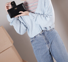 Young woman's body in a knitted sweater and jeans and her hand showing an elegant shiny black leather purse