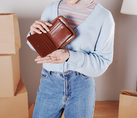 Young woman's body in a knitted sweater and jeans and her hand showing an elegant shiny brown leather purse