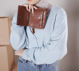Young woman's body in a knitted sweater and jeans and her hand showing an elegant shiny brown leather purse