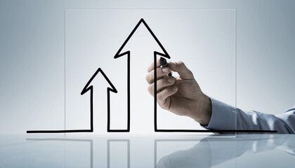 A close-up of a hand drawing a bold, upward-pointing arrow graph on a clear transparent surface with a minimal white-grey background. This image is a strong conceptual visual for business progress, fi