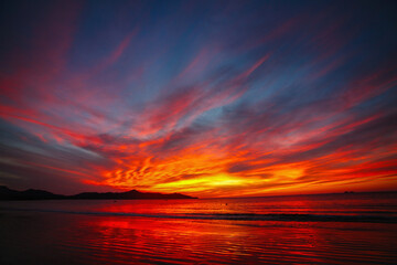 Fiery Tropical Sunset Over Ocean and Silhouetted Mountains