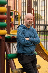 Man standing in a playground with crossed arms and serious expression