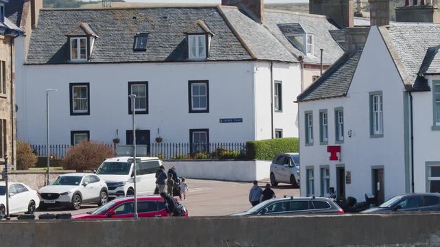 Pedestrians Walking Past Traditional Stone Houses in Cromarty