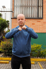 Bald man with a blue hoodie, with his hands in leather position