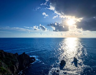 Sunny ocean view with clouds, sunlight reflections, and coastline