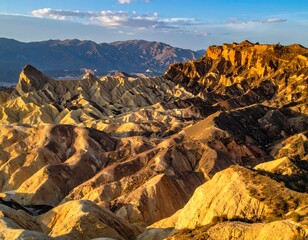 Aerial view of layered sandstone formations illuminated by golden sunlight