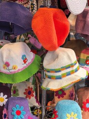 Colorful handmade crochet hats on display at a market stall