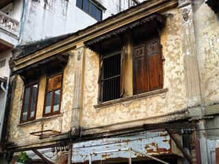 Weathered facade of an old building with wooden shutters and ornate details