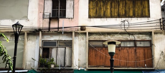 Weathered facade of an old building with wooden shutters and street lamps