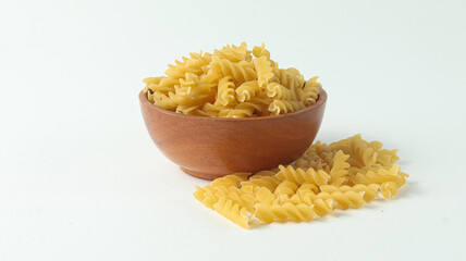 Raw Spiral Pasta in a wooden bowl on White Background
