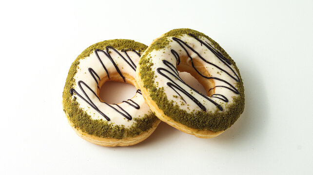 two sweet donuts with macha topping coated in sweet sugar on a white background
