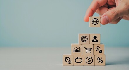 Wooden blocks stacked with business icons, hand placing globe on top.