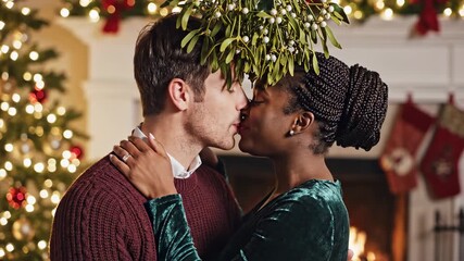 Couple shares romantic Christmas kiss under mistletoe by fireplace. - Powered by Adobe