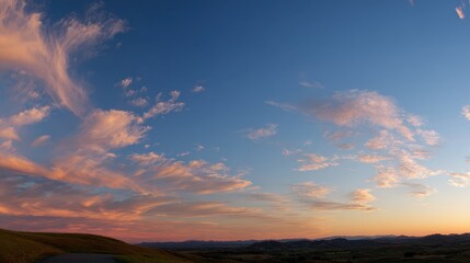 Obraz premium Calm blue sky with wispy clouds and a serene sunrise over a quiet landscape