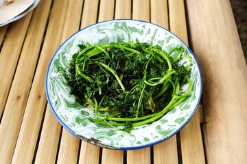Jukut Goreng or Selada Air Goreng,Popular Side Dish in Sundanese Restaurant
on traditional bamboo background 