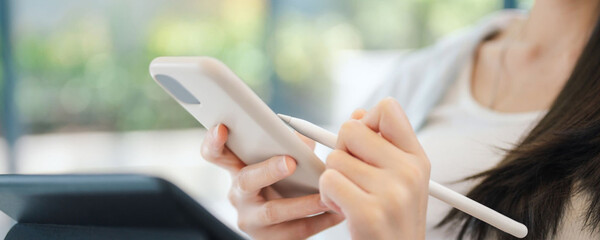 Woman using a stylus pen on a smartphone, close-up shot of hands and device
