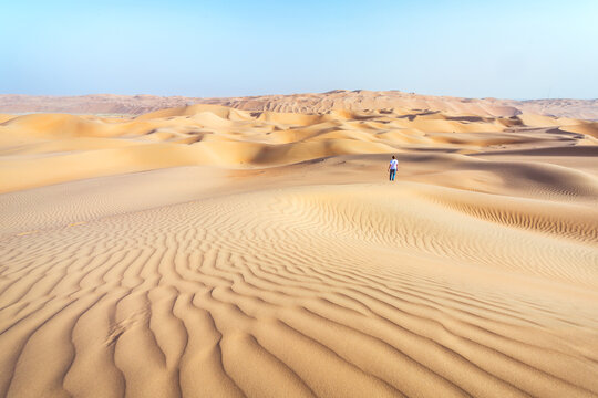 Lonely man on sand dune in the desert of Abu Dhabi