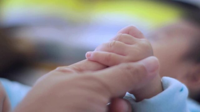 mother holding her baby's hand outdoor in the garden. trust, care or bonding concept. woman and her infant child in a backyard together in summer day.