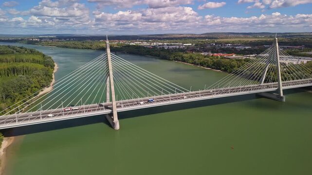 Megyeri Bridge, carrying the M0 ring road across the Danube River in Budapest, Hungary, as cars and trucks move along the modern cable-stayed structure from a drone perspective.