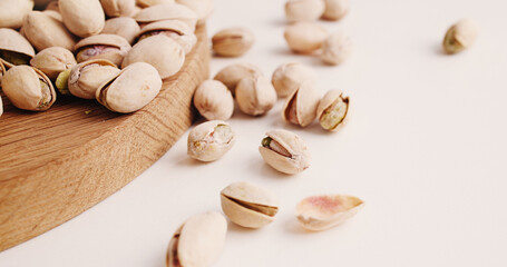 Space, nuts and pistachios on table for diet, vegan meal and healthy snack for nutrition. White background, production and roasted seeds on wooden board for organic food, natural vitamins and protein