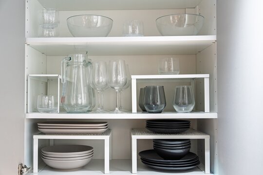 A stylish white kitchen cabinet displays glassware and dishes on sleek white shelves. This image highlights home organization and modern kitchen design, perfect for decor and storage ideas.