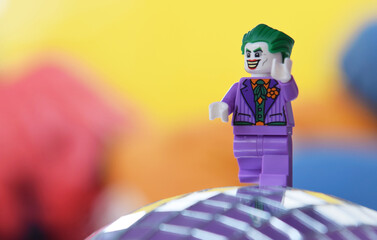 Naklejka premium Editorial illustrative image of lego minifigure of Joker in purple suit is walking.