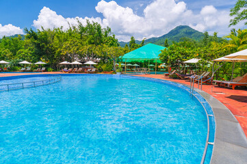 swimming pool in outdoor tropical luxury resort by sea in summer. Tourism and recreation. Landscape panorama with a pool and sun loungers and umbrellas