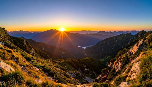 A scenic panorama of a mountain range at sunrise, with golden light bursting from the horizon and illuminating the rugged terrain