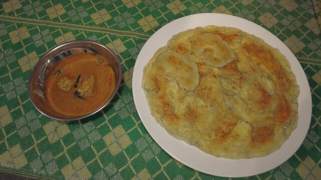 Top view of paratha with curry gravy on traditional mat in Malaysia