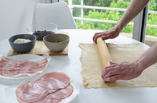 Manos estirando masa con rodillo, elaboraci&oacute;n de pan artesanal en casa con jam&oacute;n y tocineta