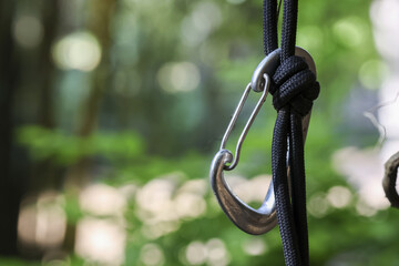 Close up of metal carabiner on black rope with secure knot. This climbing and hiking equipment symbolizes safety and sense of adventure in great outdoors