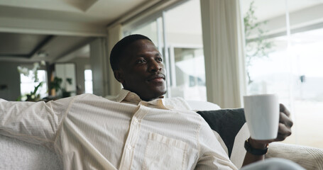 Morning, thinking and black man on sofa with coffee, calm and reflection on weekend break. Smile,...