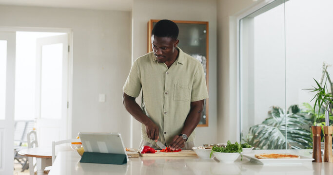 Tablet, man and cooking with vegetables in kitchen for healthy lunch, online recipe or meal prep. Tech, black person and cut ingredients in home for dinner tutorial, website steps and culinary skills - Powered by Adobe