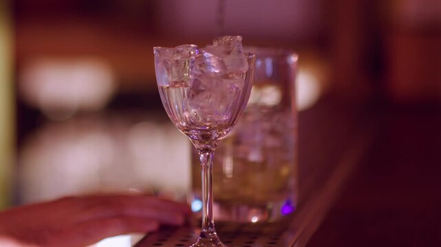 Cool liquor. Ice cube beverage. Bartender making cold aperitif glass on counter. Hand mixing cocktail with professional long spoon.