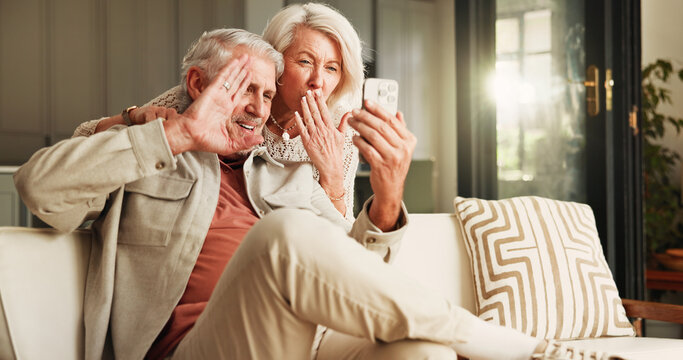 Gesture, phone and video call with old couple in living room of home together for break or wellness. App, blowing kiss and wave with happy senior people in apartment for bonding or communication - Powered by Adobe