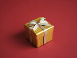 Golden gift box tied with satin ribbon on deep red festive background