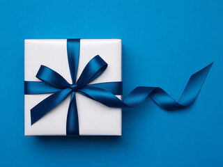 White gift box tied with blue satin ribbon on matching blue background
