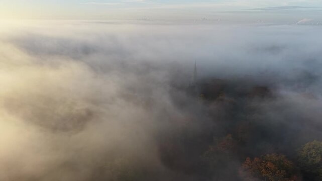 Church steeple rises through misty morning fog Epping Forest UK drone,aerial