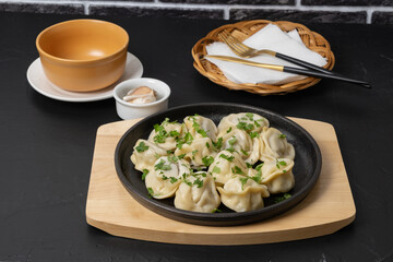 Delicious dumplings served on a black plate in a cozy dining setting