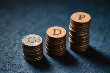 Three stacks of coins, topped with wooden circles lettered g, d, p respectively, against a textured blue background