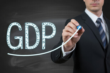 Businessman drawing a white gdp line graph on a chalkboard background symbolizing economic trends and financial performance