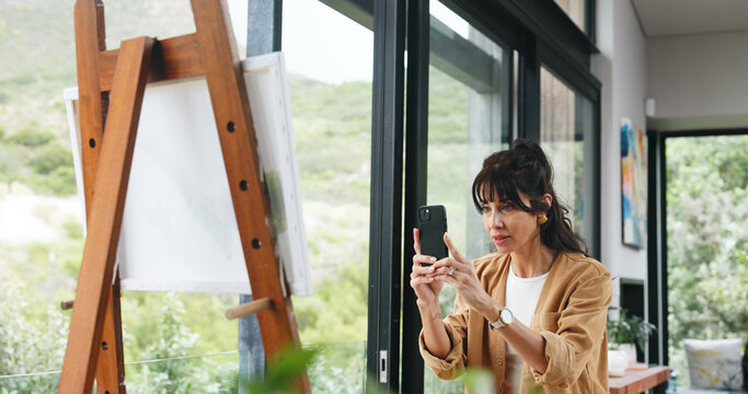 Painting, phone and picture with woman in workshop for design reference, artist project and contact. Talent inspiration, gallery artwork and canvas with mature person in studio for photography