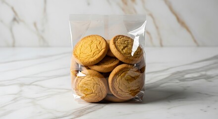 Delicious golden brown cookies in a clear plastic bag on a white marble surface.
