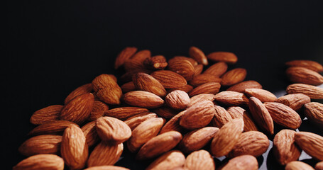 Black background, nuts and almonds in studio for diet, vegan meal and healthy snack for nutrition. Space, food production and harvest of roasted seeds for organic supplements, natural fats or protein