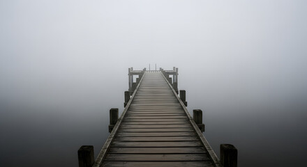 Obraz premium Mysterious Wooden Pier Extending into Thick White Fog Over Calm Water