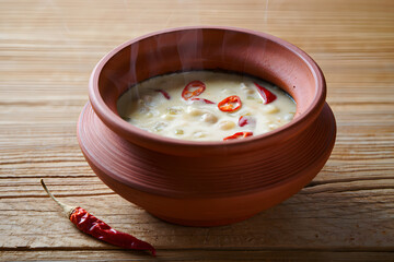 Spicy yogurt dip in a clay pot with chili peppers