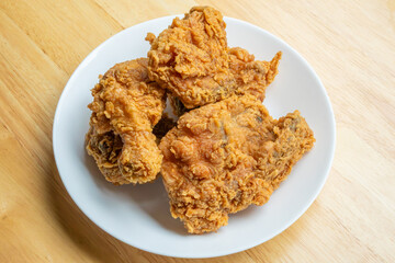 Crispy fried chicken in white plate on wood table
