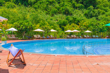 swimming pool at tropical luxury resort in summer. Tourism and recreation. Landscape with a pool and sun beds and umbrellas