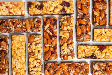 Colorful assortment of energy bars made with nuts, fruits, and grains arranged on a clean surface